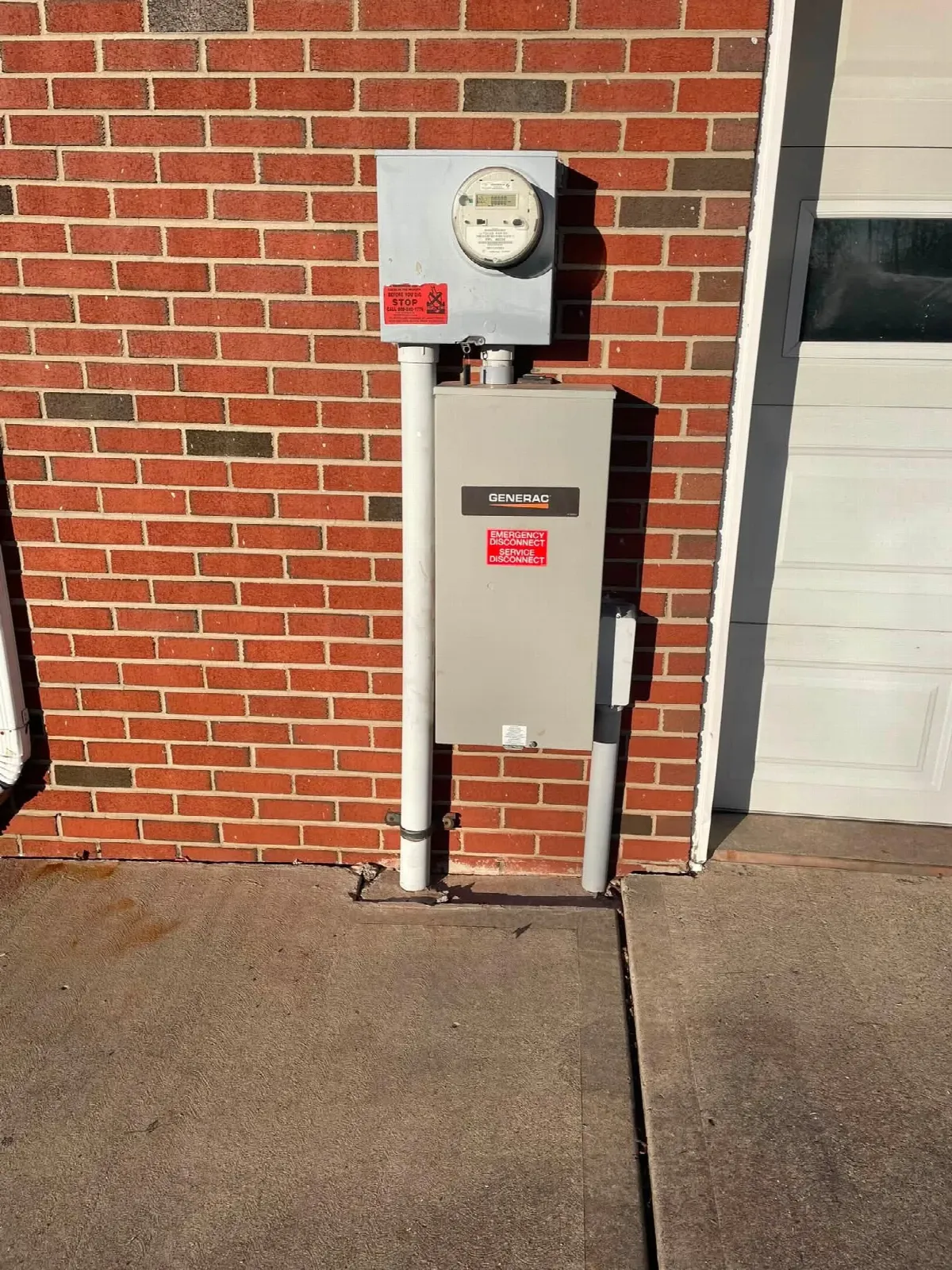Generac transfer equipment installed below an electric meter on a brick wall