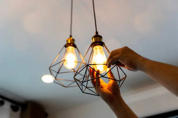 Electrician servicing bulbs in pendant light fixtures